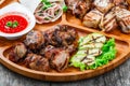 Assorted delicious grilled meat and vegetables with fresh salad and bbq sauce on cutting board on wooden background Royalty Free Stock Photo