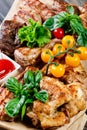 Assorted delicious grilled meat and vegetables with fresh salad and bbq sauce on cutting board on wooden background close up Royalty Free Stock Photo