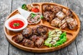 Assorted delicious grilled meat and vegetables with fresh salad and bbq sauce on cutting board on wooden background Royalty Free Stock Photo