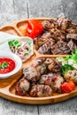 Assorted delicious grilled meat and vegetables with fresh salad and bbq sauce on cutting board on wooden background Royalty Free Stock Photo