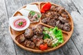 Assorted delicious grilled meat and vegetables with fresh salad and bbq sauce on cutting board on wooden background close up Royalty Free Stock Photo