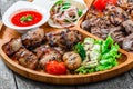 Assorted delicious grilled meat and vegetables with fresh salad and bbq sauce on cutting board on wooden background close up. Royalty Free Stock Photo