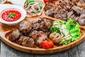 Assorted delicious grilled meat and vegetables with fresh salad and bbq sauce on cutting board on wooden background close up. Royalty Free Stock Photo