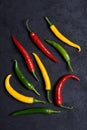 Assorted different colored chili peppers on dark background