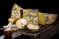 Assorted different gourmet cheeses on a wooden board on a dark background. Various types of cheese: hard and soft with mold. Low Royalty Free Stock Photo