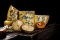 Assorted different luxury gourmet cheeses on a wooden board on a dark background. Various types of cheese: hard and soft with mold Royalty Free Stock Photo