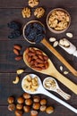 Assorted different nuts, prunes, pumpkin seeds in spoons on a dark wooden background Royalty Free Stock Photo