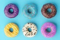 Assorted donuts with colorful icings on blue background.