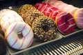 Assorted donuts on shelf in Bakery shop. Sweet icing sugar food. Dessert colorful snack. Glazed sprinkles.