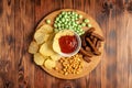 Assorted dry snacks on a wooden board. Chips, peanuts, croutons, wasabi Royalty Free Stock Photo