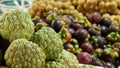 Assorted exotic fruits on stall in market. Bunch of sugar apples placed on blurred background of longans and mangosteens on stall