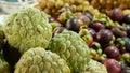 Assorted exotic fruits on stall in market. Bunch of sugar apples placed on blurred background of longans and mangosteens on stall