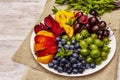 Assorted fresh berries of a cherry, gooseberry, blueberries, slices of ripe peach, plum and apricot, fragrant mint on a plate Royalty Free Stock Photo