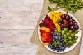 Assorted fresh berries of a cherry, gooseberry, blueberries, slices of ripe peach, plum and apricot, fragrant mint on a plate Royalty Free Stock Photo