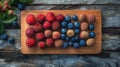 Assorted fresh berries and lychee on a rustic wooden board Royalty Free Stock Photo