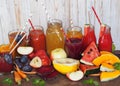 Assorted fresh fruits and freshly prepared cocktails of different colors on a wooden table with a white wooden background.Rustic