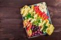 Assorted fresh fruits on plate. Apple, grapes, kiwi, pineapple, grapefruit, orange, banana and mint on wooden table