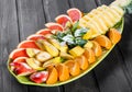 Assorted fresh fruits on plate. Apple, orange, pineapple, grapefruit, banana and mint on dark background. Royalty Free Stock Photo