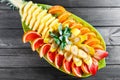 Assorted fresh fruits on plate. Apple, orange, pineapple, grapefruit, banana and mint on dark background. Royalty Free Stock Photo