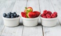 Assorted fresh juicy berries in three tiny bowls Royalty Free Stock Photo