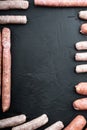 Assorted fresh raw pork, beef and chicken sausages, frame concept, top view with space for text, on black background Royalty Free Stock Photo