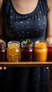 Assorted fruit jams, glass jars on wooden plate, held in closeup by woman