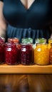Assorted fruit jams, glass jars on wooden plate, held in closeup by woman