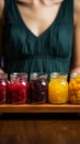 Assorted fruit jams, glass jars on wooden plate, held in closeup by woman