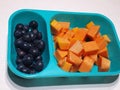 An Assorted Fruit Platter on a Blue tiffin. Papaya, fresh black grapes Royalty Free Stock Photo