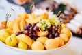 assorted fruit on a white plate. apricots, grapes, peaches and cherry plums