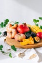 Assorted fruits in a wooden board on a marble background, green ivy mango, peach, plum, pear, pomegranate