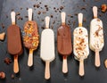 Assorted gourmet ice cream popsicles with toppings on black background
