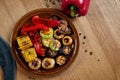 Assorted grilled vegetables - mushrooms, zucchini, peppers, corn in a ceramic plate on a wooden background. Vegetarian warm salad Royalty Free Stock Photo