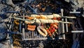 Assorted grilled vegetables, sausages and bread over a barbecue grid fire place, shot from top