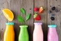 Assorted healthy fruit smoothies in bottles with ingredients, top view over wood