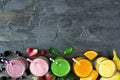 Assorted healthy fruit smoothies, top view bottom border against a dark background