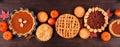 Assorted homemade fall pies. Top view table scene on a dark wood banner background.