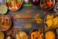 Assorted indian food set on wooden background. Dishes and appetisers of indeed cuisine, rice, lentils, paneer, samosa, spices. Royalty Free Stock Photo