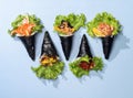 Assorted japanese wraps Spicy TAMAGO, CALIFORNIA wrap, POKE SALMON Skin, SPICY TUNA roll topping with salad leaves isolated on sky