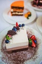 Assorted large pieces of different cakes: three chocolate, carrot, strawberry, chocolate. Cakes are decorated with berries