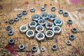 Assorted metal hex nuts shaping a circle on wooden workbench stained grunge textured surface