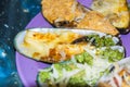 Assorted multicolored baked mussels on a violet plate on a table