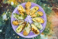 Assorted multicolored baked mussels on a violet plate on a table