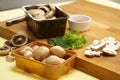 Assorted mushrooms in plastic containers, arranged on wooden chopping board with parsley