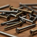 Assorted nails and screws lie scattered on a wooden surface. The nails are metallic, Royalty Free Stock Photo