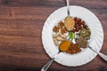 Assorted nuts in white bowl, plate on wooden surface. Top view with copy space Royalty Free Stock Photo