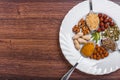 Assorted nuts in white bowl, plate on wooden surface. Top view with copy space Royalty Free Stock Photo