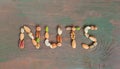 Assorted nuts on wooden background spelled with word nuts. Banner nuts Royalty Free Stock Photo