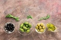 Assorted olives in glass bowls, olive oil and rosemary in a row on a dark background. Top view, flat lay, copy space Royalty Free Stock Photo