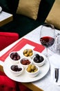 Assorted olives and sun-dried tomatoes with a glass of red wine. Place for text Royalty Free Stock Photo